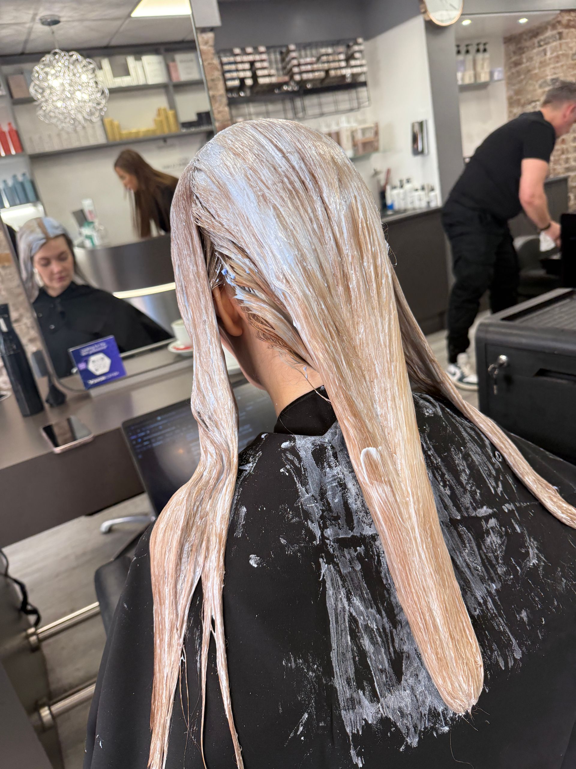 Hair colour correction process with lightener applied showing sectioning and technical work in progress