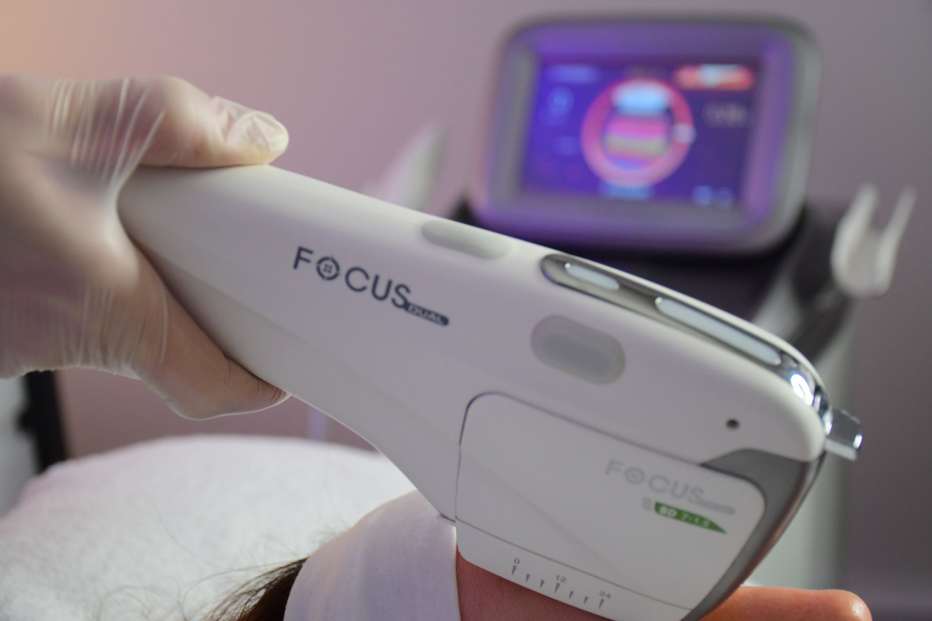A focus Dual® High Intensity Focused Ultrasound Handpiece being used on the forehead with the Focus Dual® machine visible in the background.