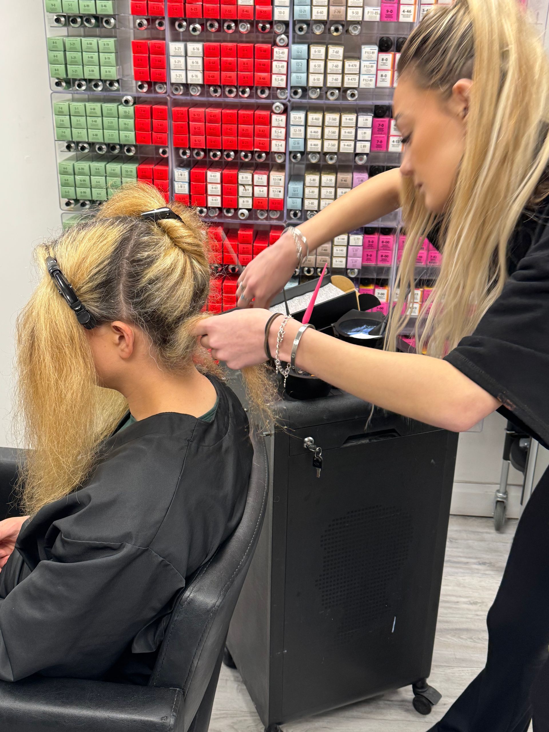 Hair colour correction in progress with visible sectioning and uneven blonde tones being assessed