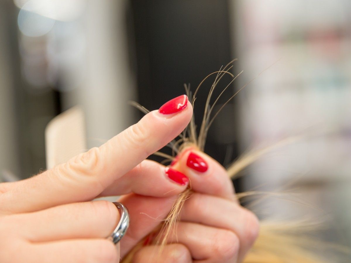 Close-up assessment of soft textured hair being examined for condition and integrity in salon.