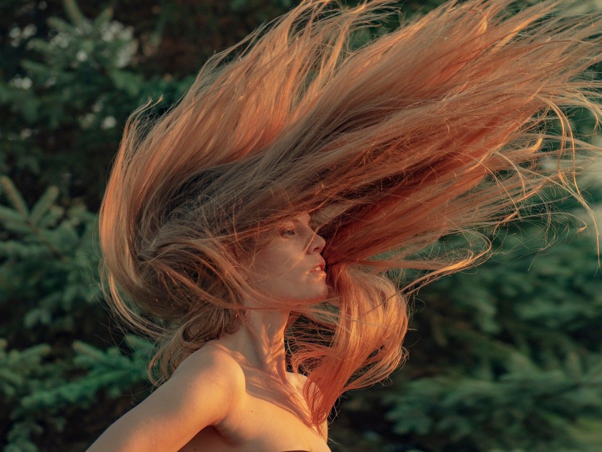 Sunlight reflecting through long warm-toned hair outdoors during summer.