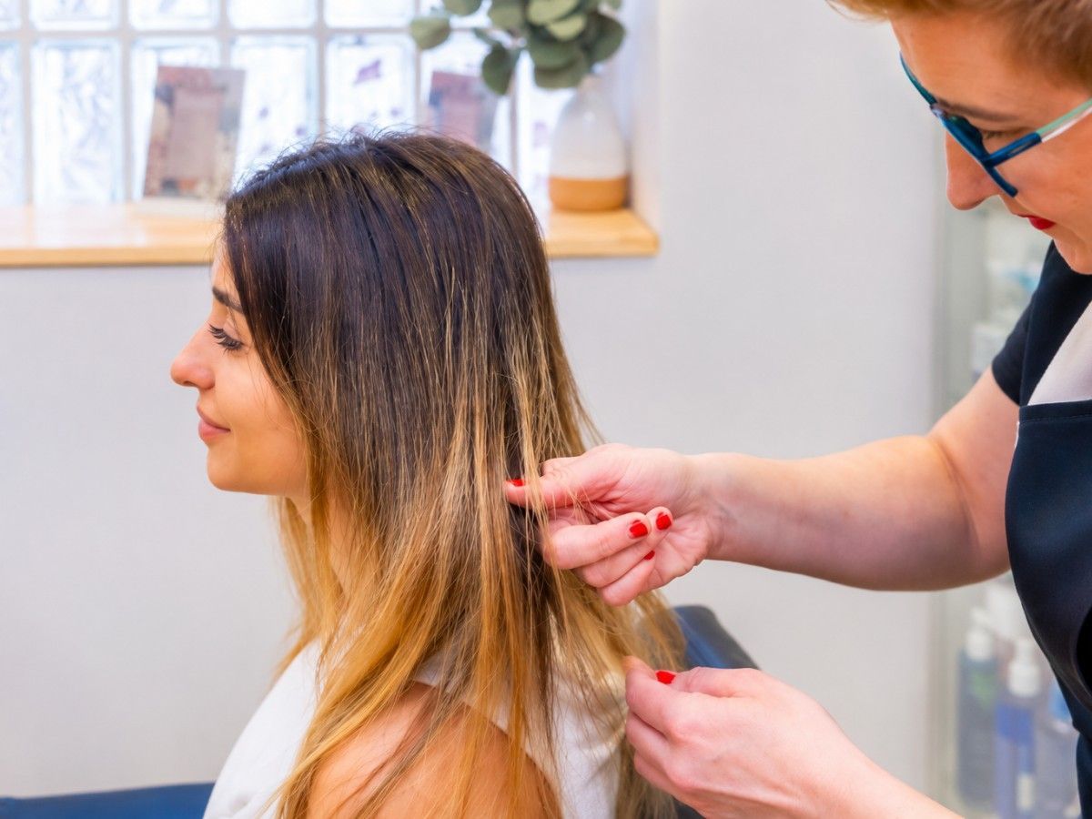 Stylist assessing a section of hair during a colour consultation and strand test evaluation