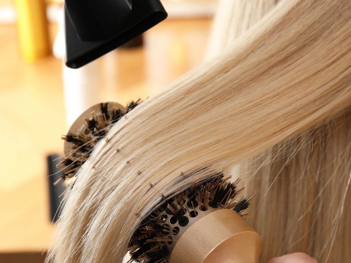 Professional blow-dry styling creating smooth blonde hair