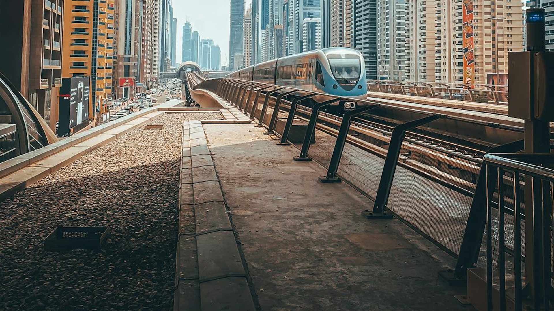 A train is going down the tracks in a city.