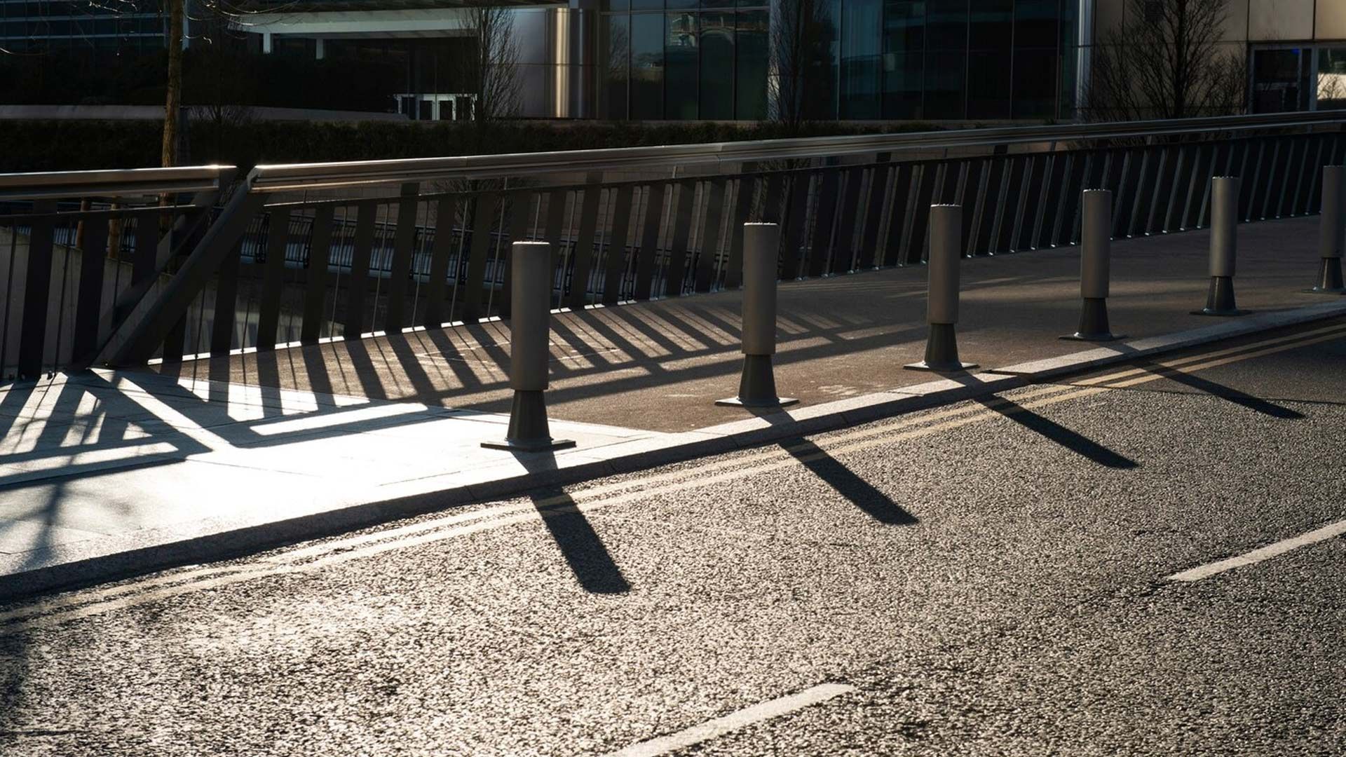 A shadow of a railing on the side of a road
