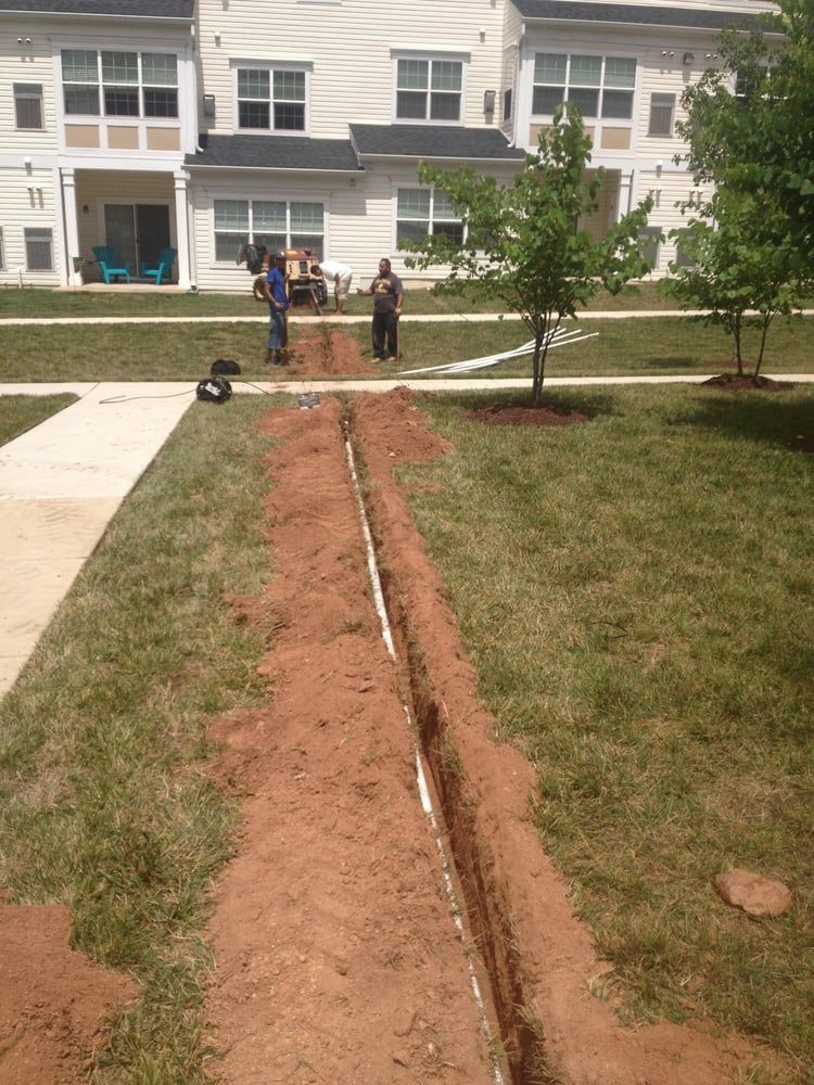 A man is digging a hole in the ground in front of a house