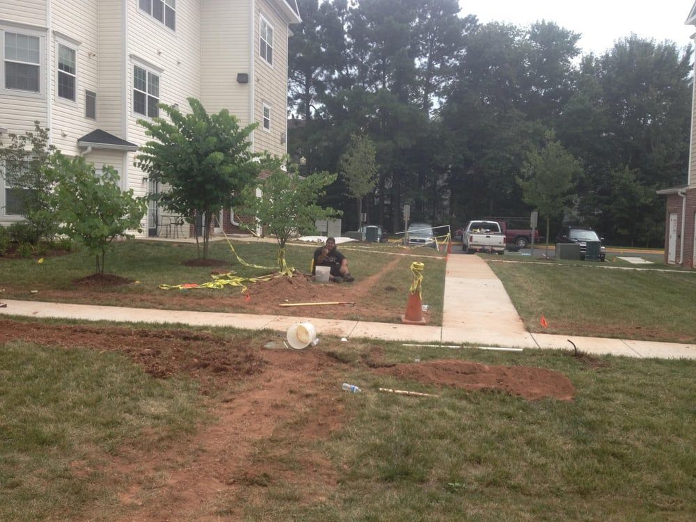 A man sits in the dirt in front of a building