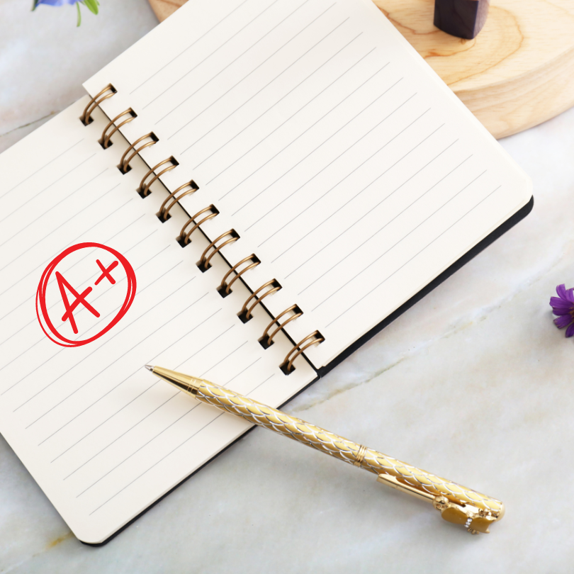 A notebook with an a+ written on it next to a pen