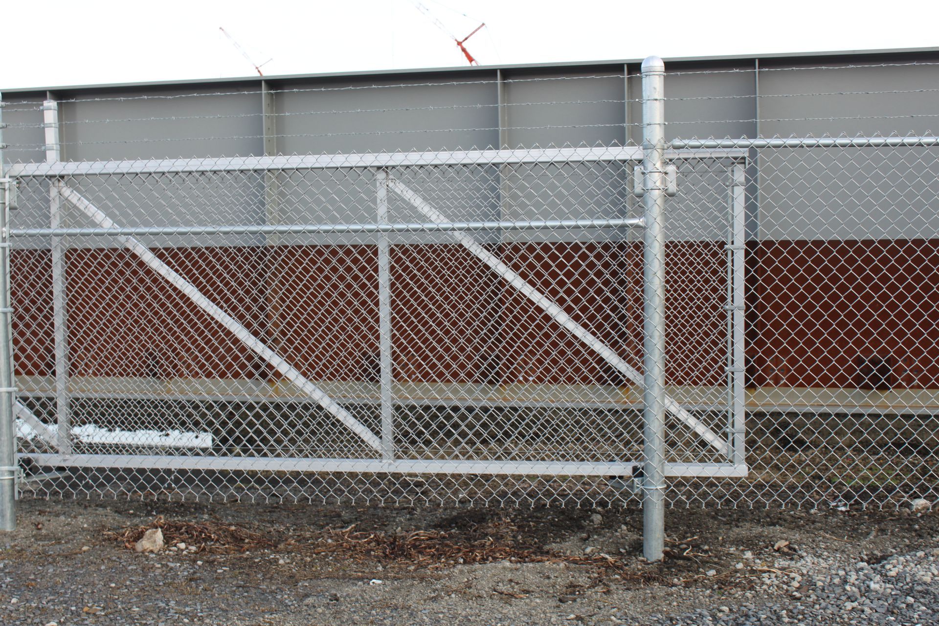 A chain link fence with a gate in front of a brick building.