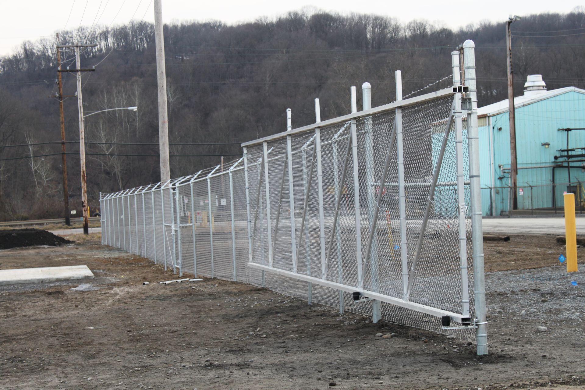 A chain link fence is sitting in the middle of a dirt field.