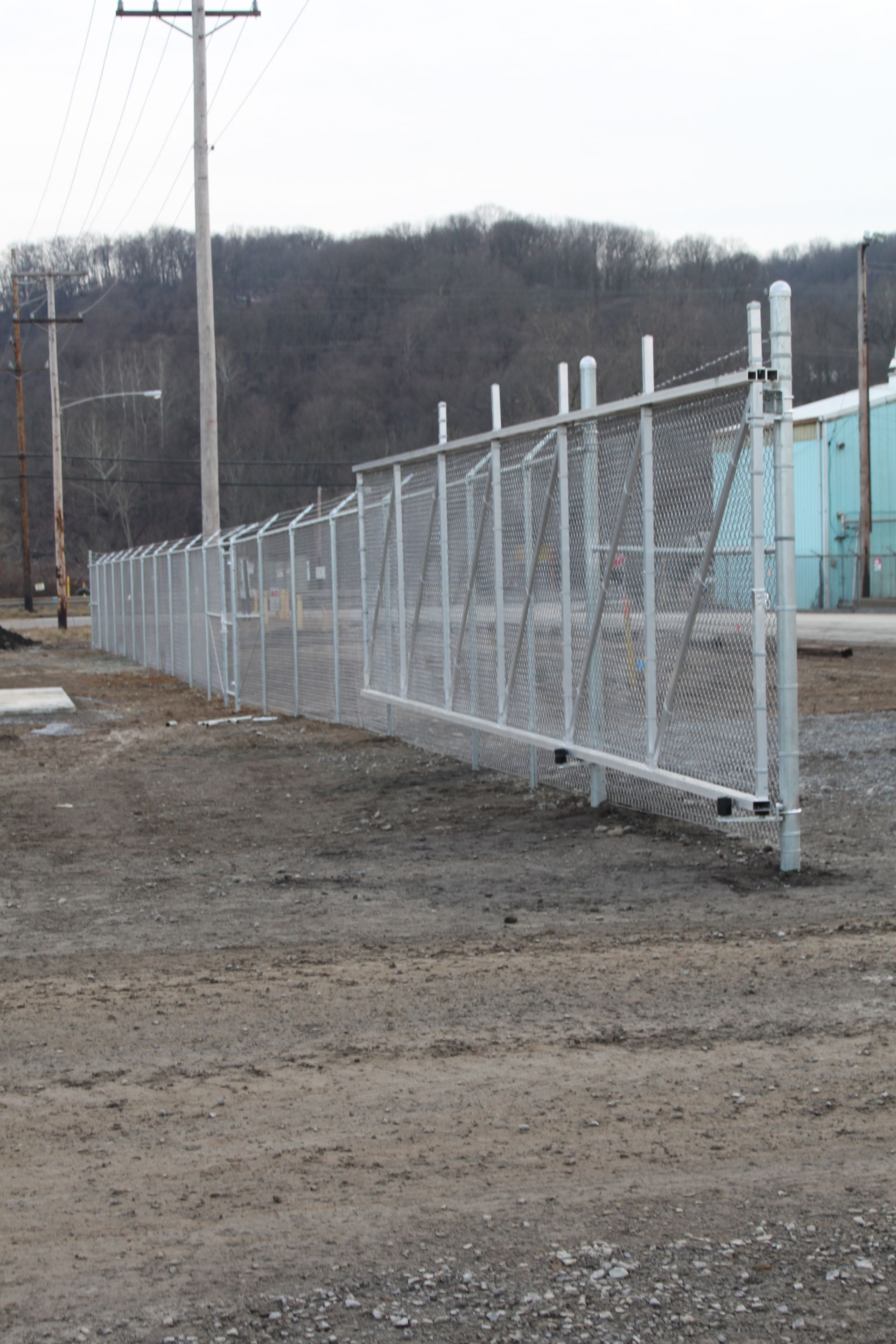 A chain link fence is sitting in the middle of a dirt field.