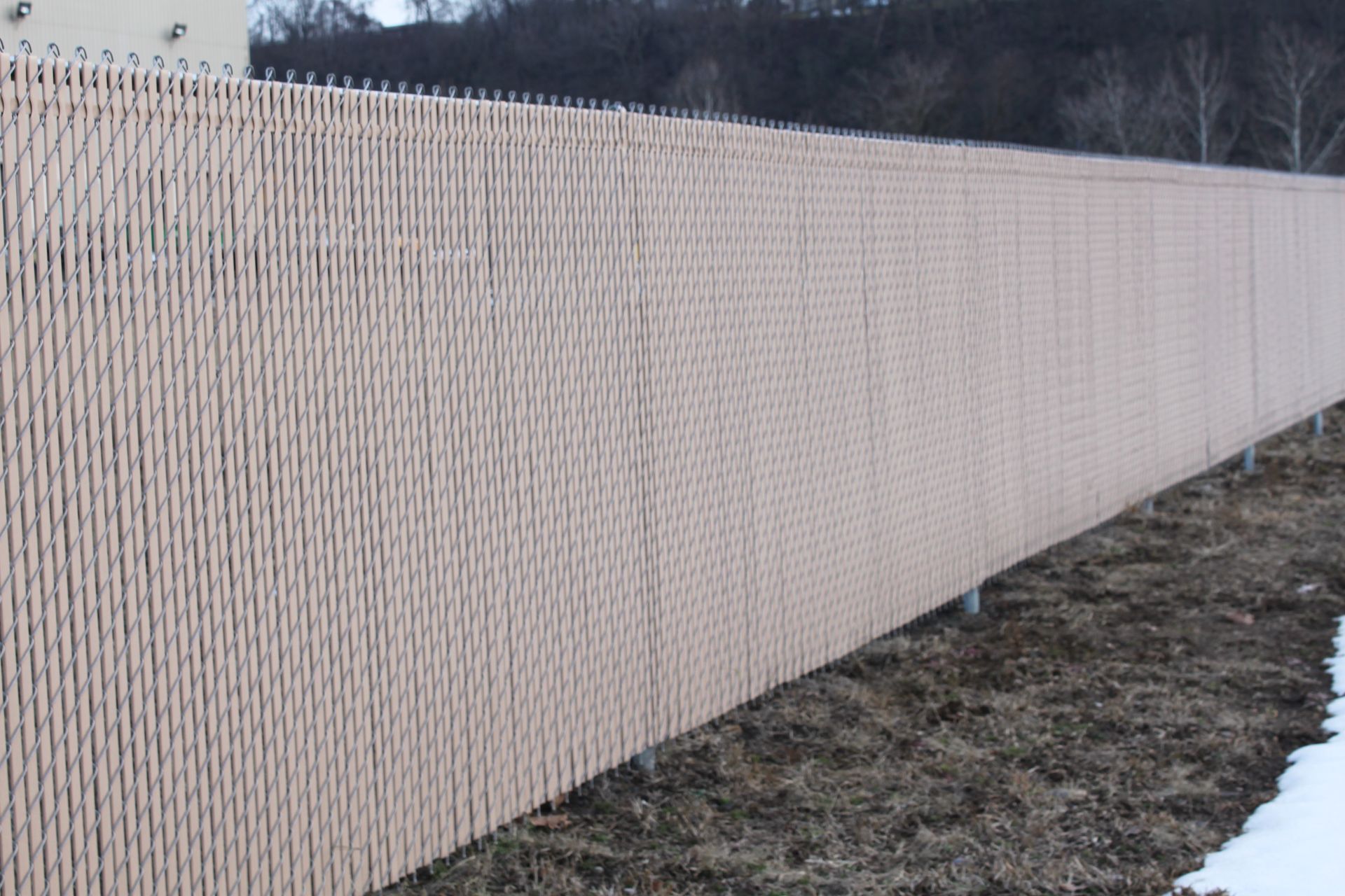 A long chain link fence surrounds a grassy field.