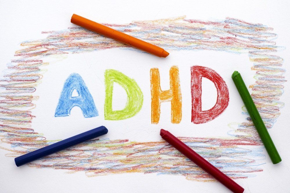 the word adhd is written on a piece of paper with crayons .