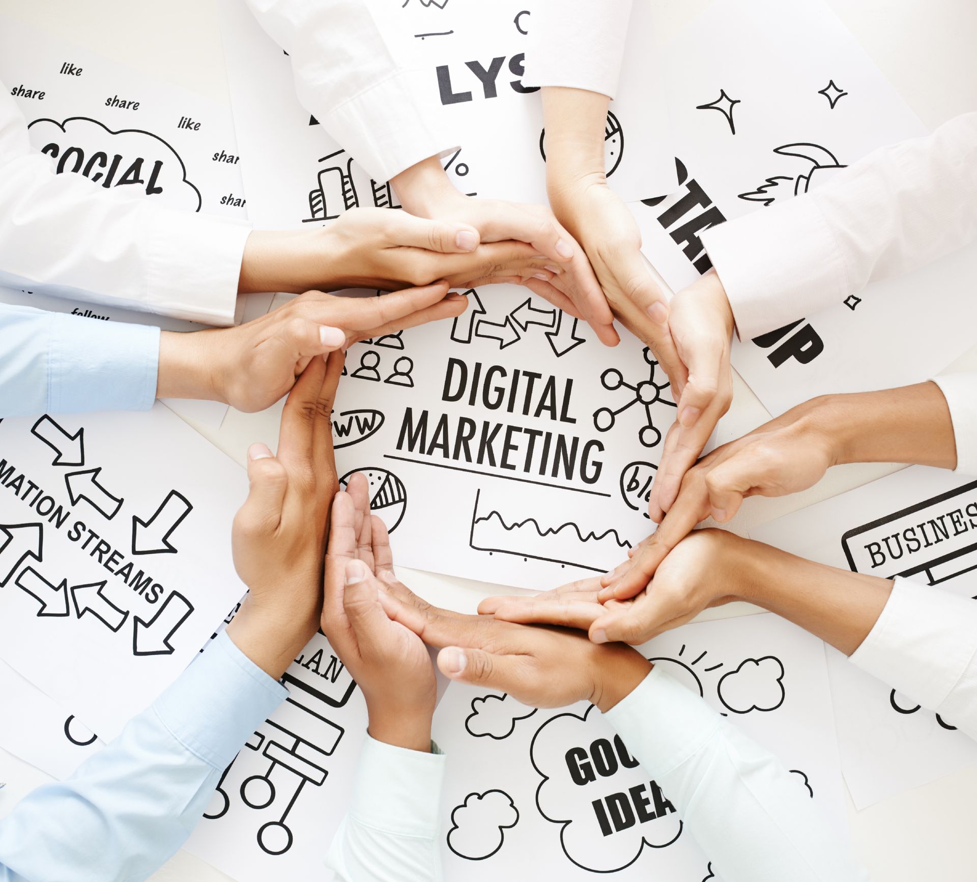 Several people join hands around a white sheet with sketches and the text 