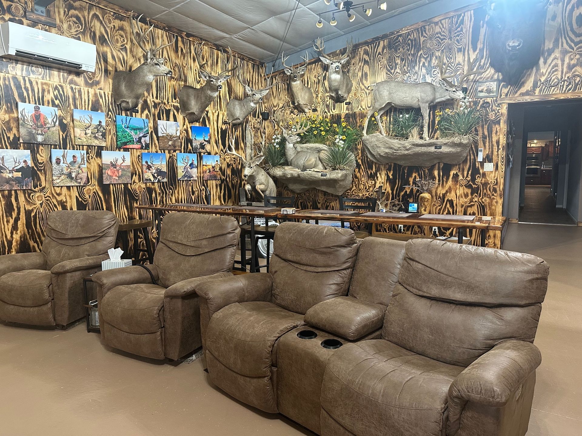 Lounge area with recliner seats, animal trophies, and nature-themed wall décor.