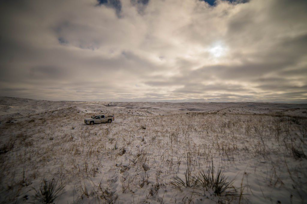 A lone pickup truck in a snowy field under a cloudy sky.