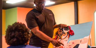 A Man is Holding a Painting in Front of a Woman