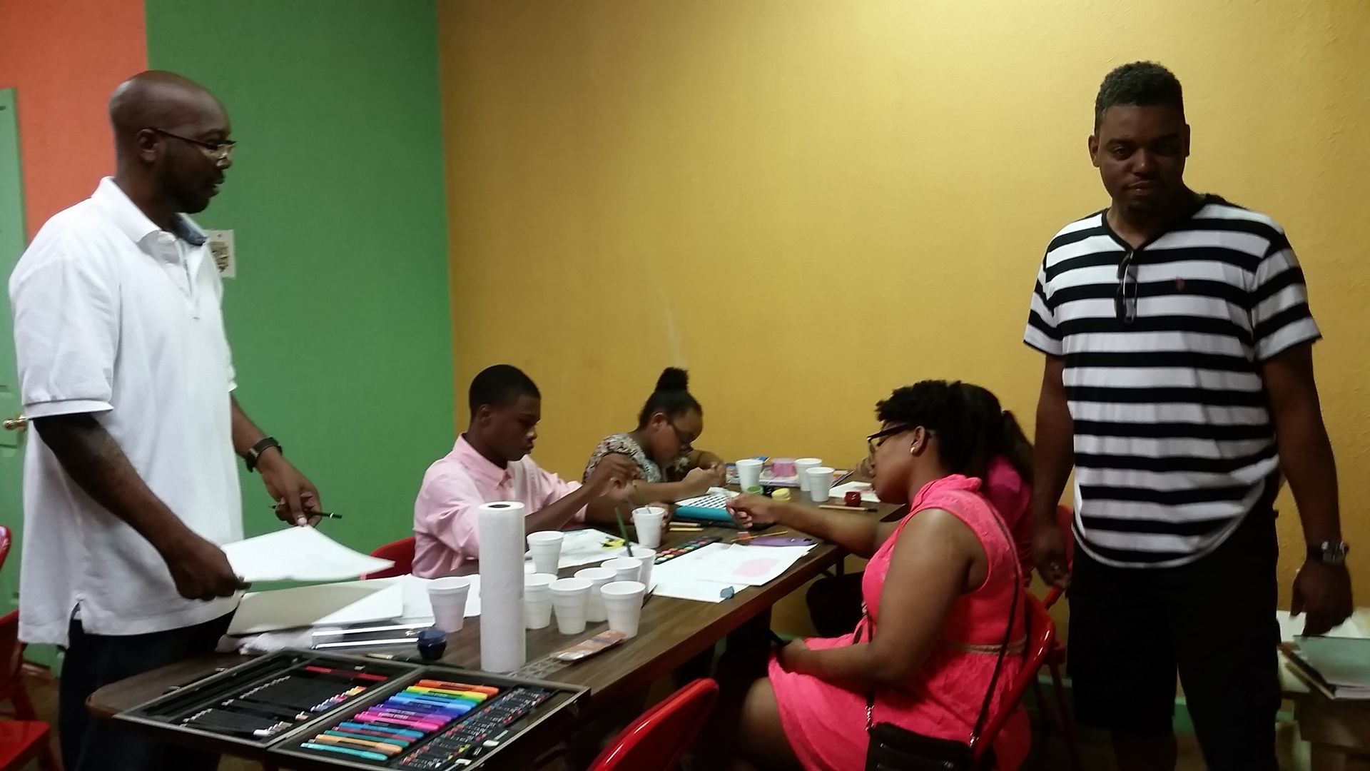A Group of People Are Sitting at a Table With Colored Pencils