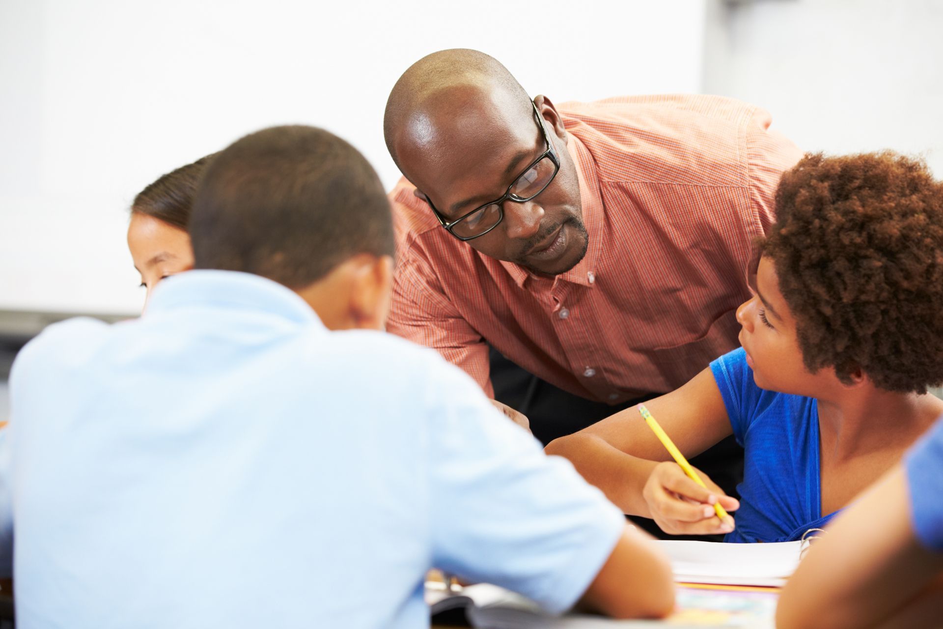 A Man is Teaching a Group of Children in a Classroom