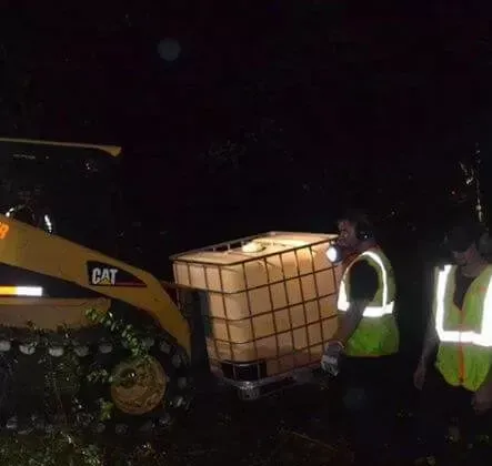 A man is standing next to a large container in front of a cat tractor.