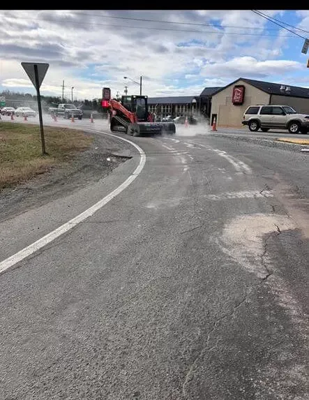 A forklift is driving down a road next to a building.