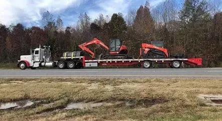 A semi truck is carrying an excavator on a flatbed trailer.