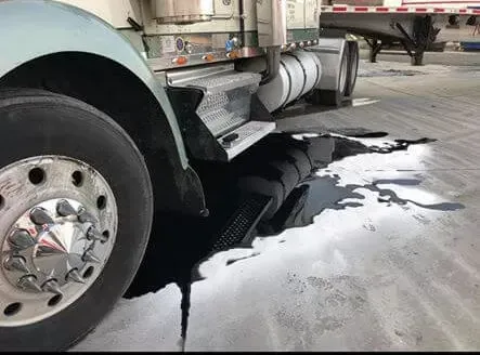 A semi truck is parked in a garage with a hole in the ground.