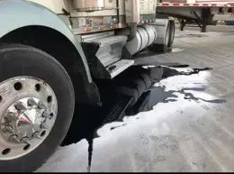 A semi truck is parked in a garage with a hole in the ground.