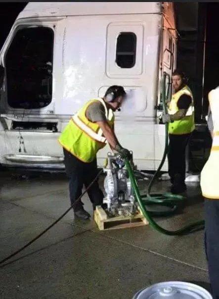 A man in a yellow vest is pumping gas into a truck