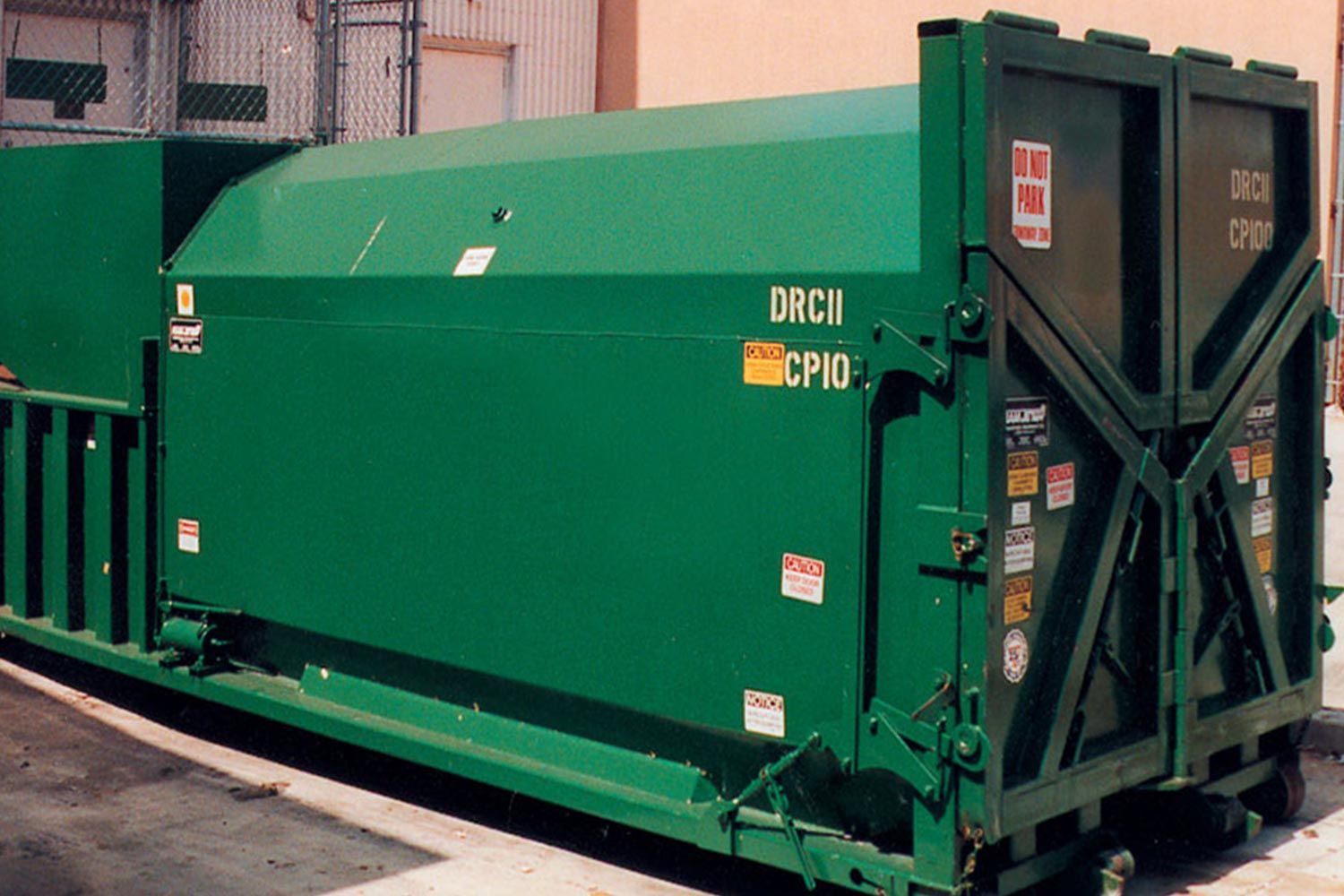 A large black dumpster is sitting on top of a lush green field.