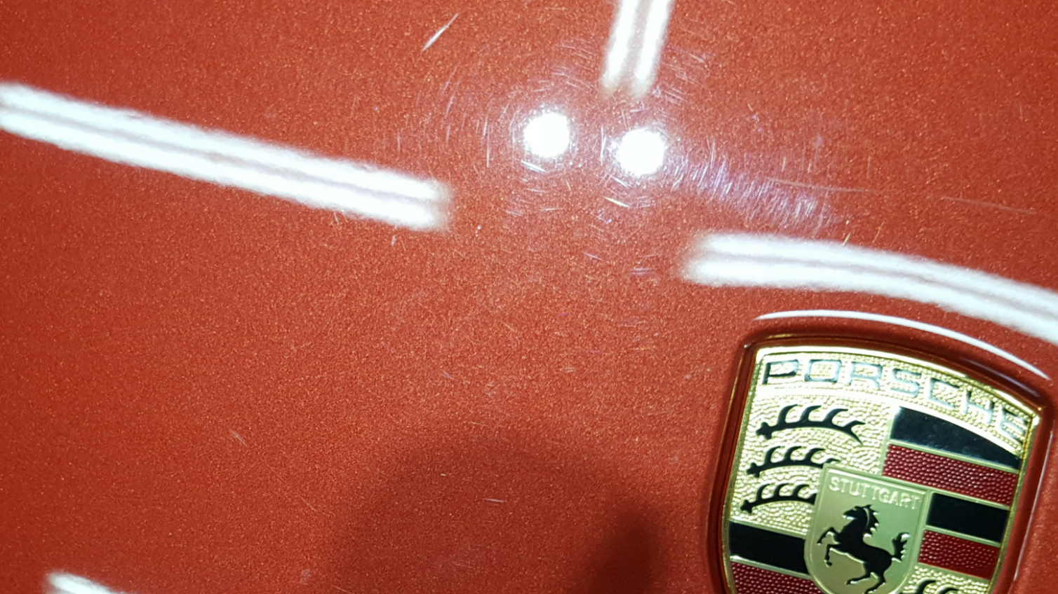 Red Porsche car body with a badge and a few scratches.