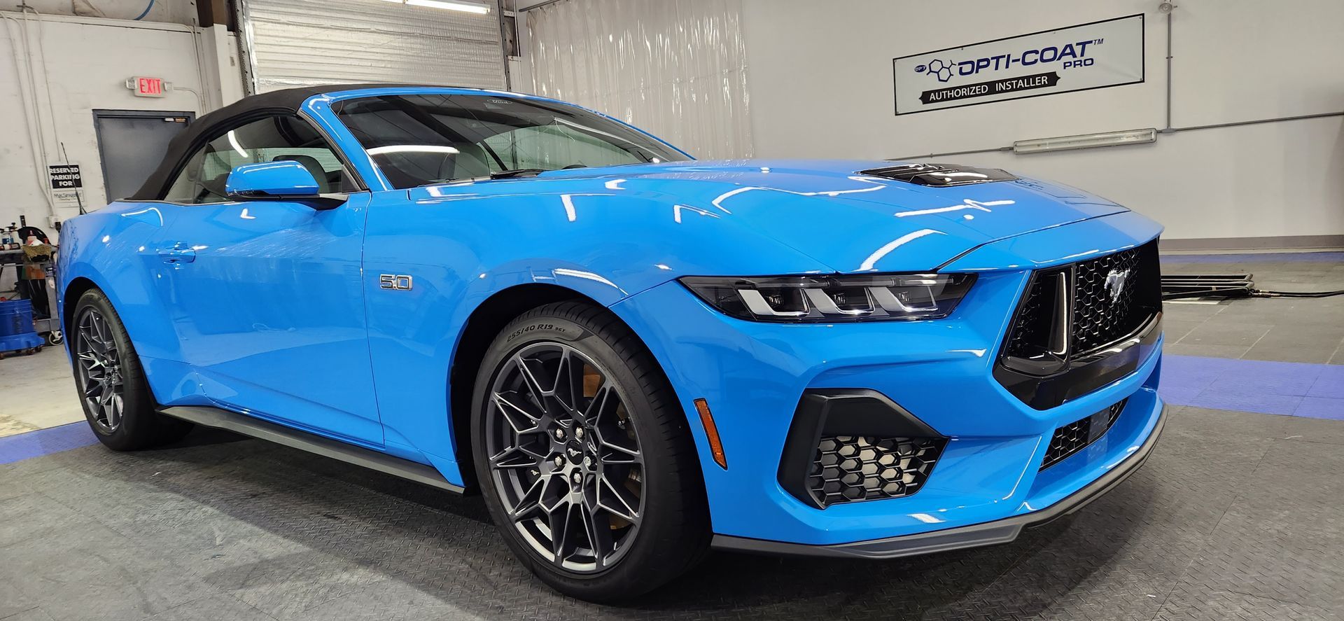 Blue Ford Mustang convertible in a garage.