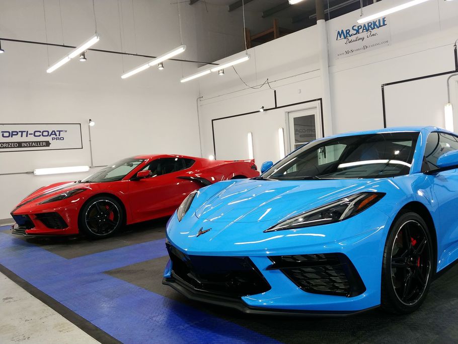 Two Chevrolet Corvette sports cars, red and blue, parked inside a garage.
