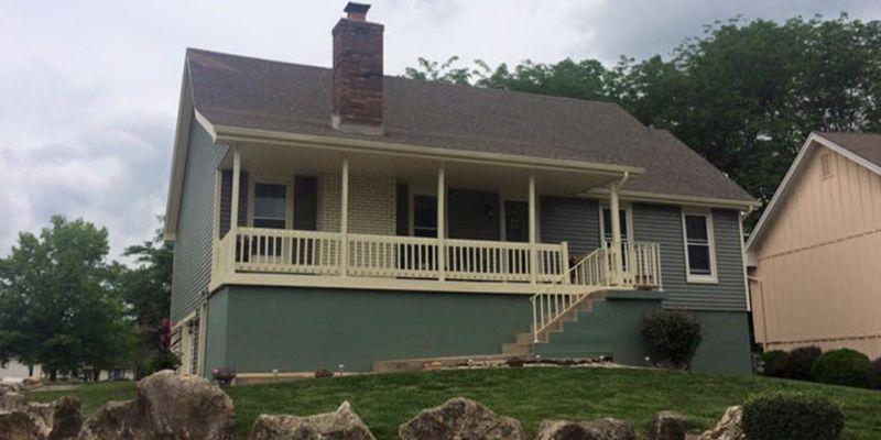 A house with a porch and a chimney on top of it