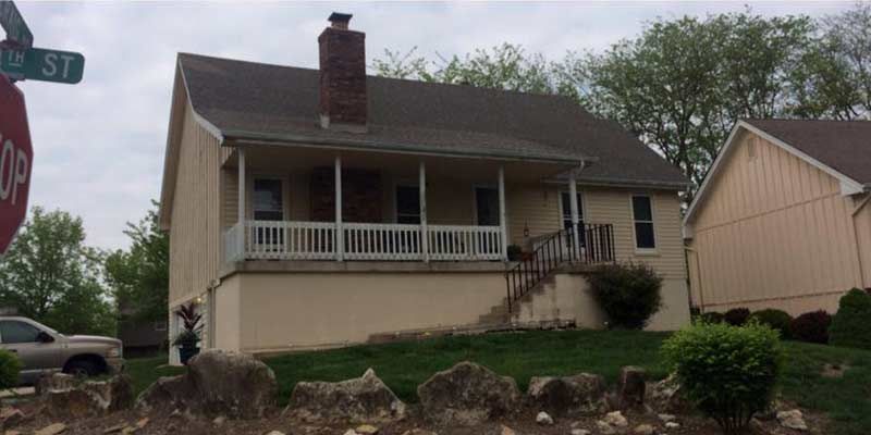 A house with a porch and a stop sign in front of it