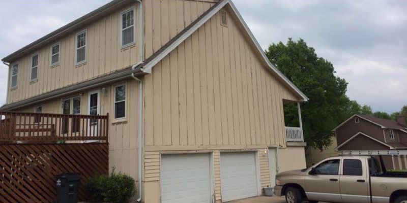 A truck is parked in front of a house with two garage doors