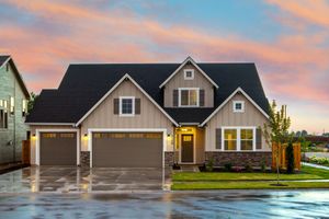 A large house with two garage doors and a driveway in front of it.