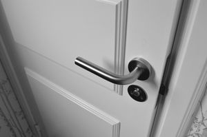 A close up of a door handle on a white door