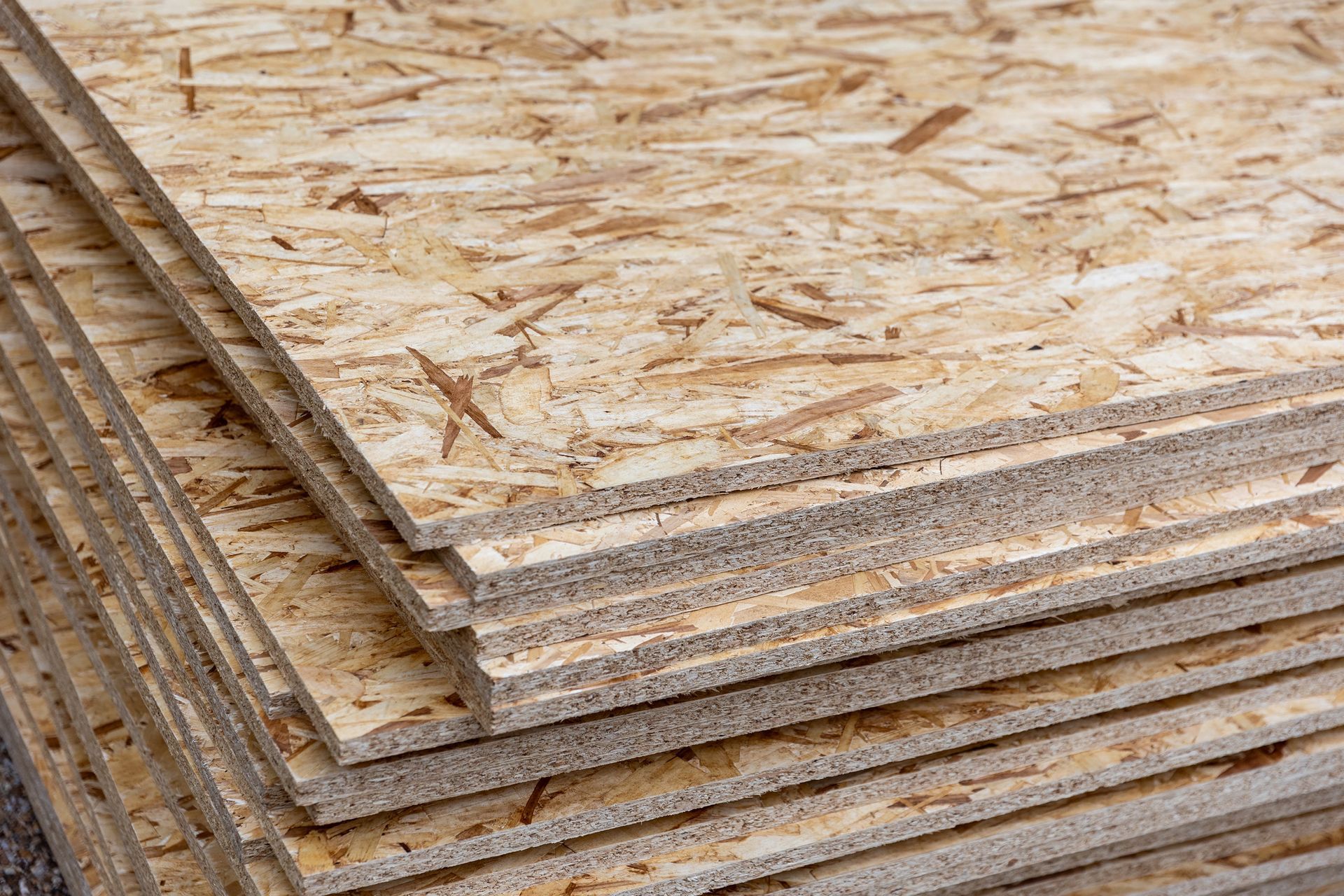 Pila de tableros de virutas orientadas (OSB), con virutas de madera de color beige y marrón visibles.