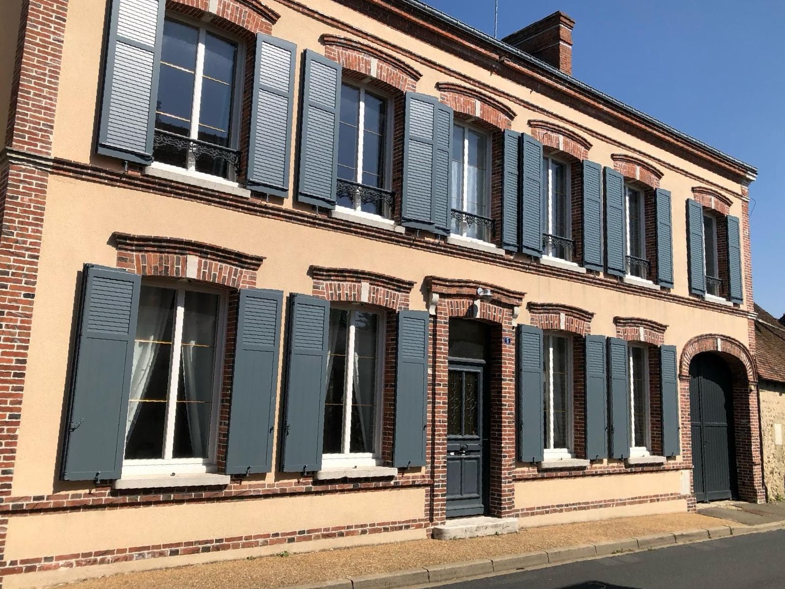 Un grand bâtiment en briques avec beaucoup de fenêtres et de volets