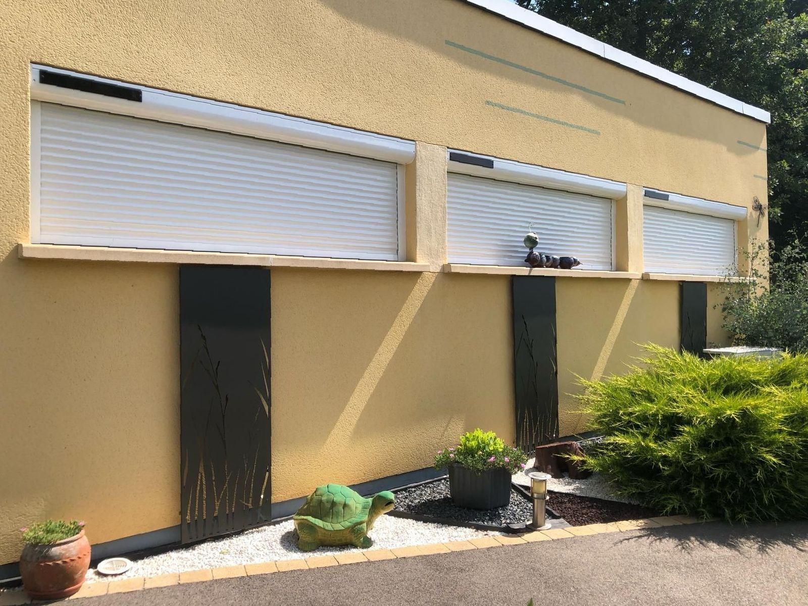Un bâtiment jaune avec des volets blancs aux fenêtres.