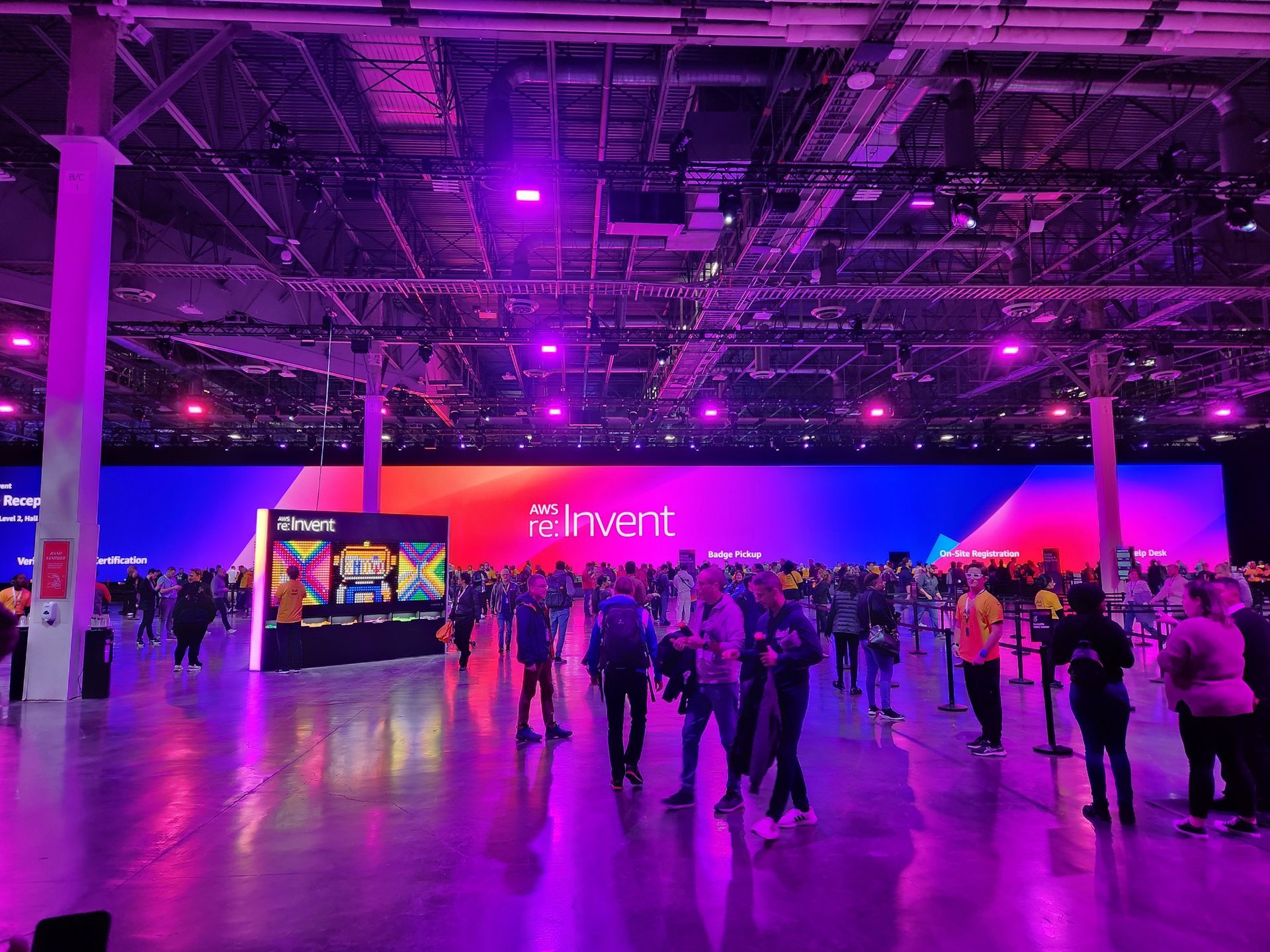 A group of people are standing in a large room with purple lights.