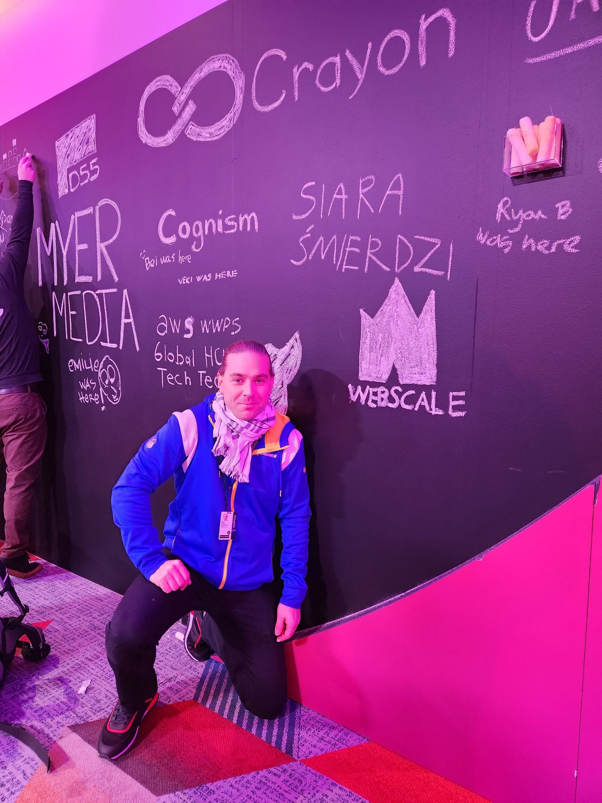 A man is kneeling in front of a blackboard that says crayon