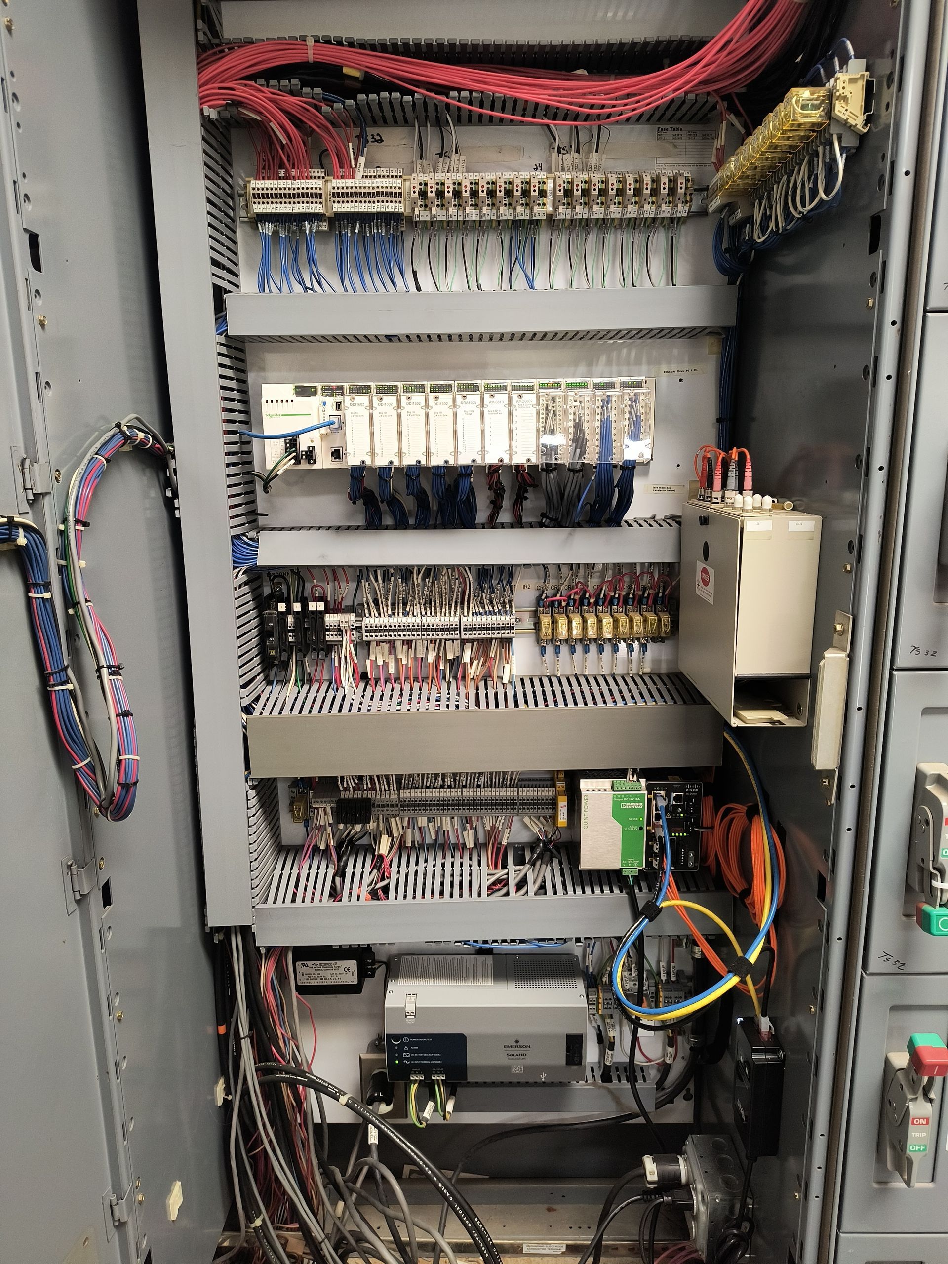 Open electrical control panel with rows of wiring, relays, and circuit modules.