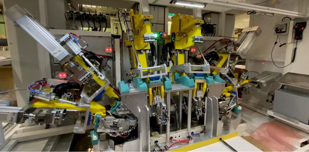 Chaîne de montage robotisée avec des machines jaunes et bleues dans un environnement d'usine.