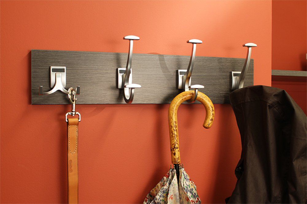 Wooden wall coat rack with silver hooks holding a yellow umbrella and hanging items on an orange wall