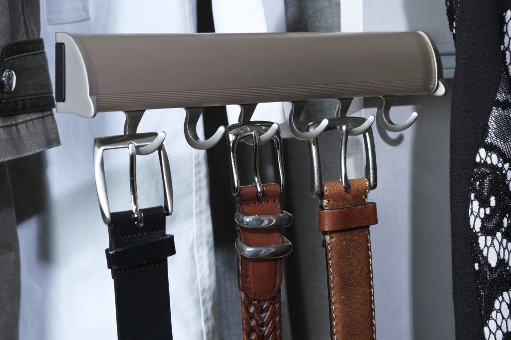 Row of hanging belts in black, brown, and tan on a clothing rack