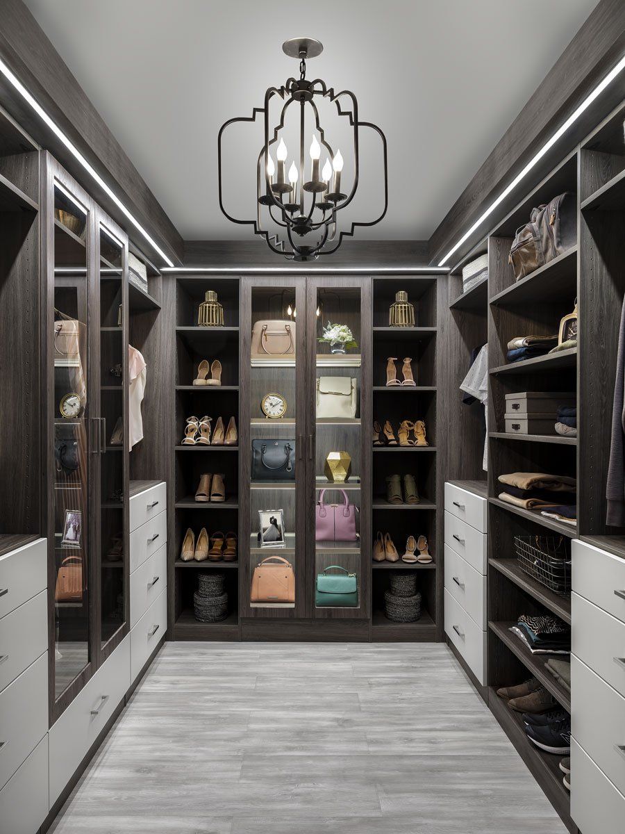 a walk in closet with lots of shelves and a chandelier