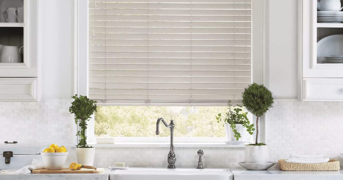 A kitchen with a sink and a window with blinds.