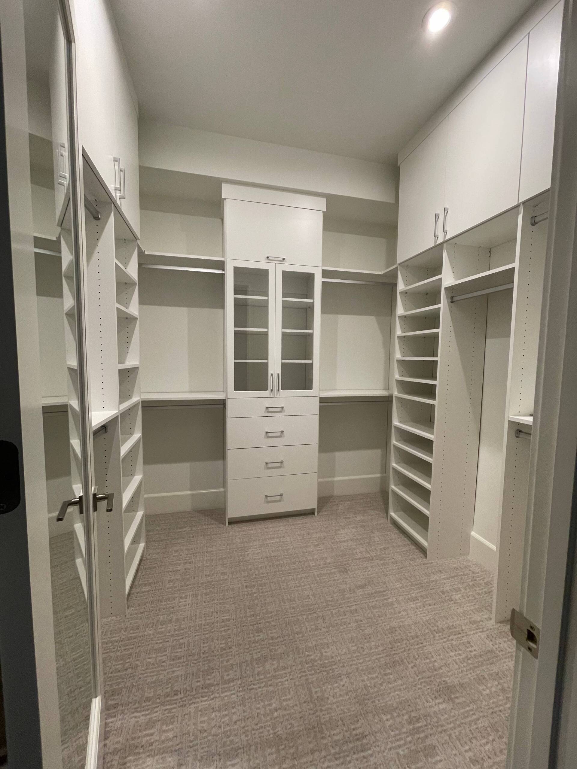 a walk in closet system with lots of shelves and drawers .